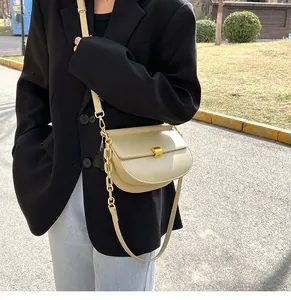Dettaglio borsa a sella beige con trama in pelle opaca e chiusura a girello dorata