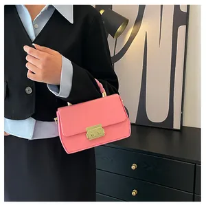 Detailed shot of a pink crossbody bag with a gold metal clasp and a woven handle design
