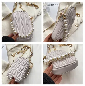 Detail view of cream quilted mobile bag with pearl handle and rhinestone chain strap
