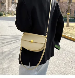 Borsa a sella in pelle beige con fibbia in metallo dorato indossata da una modella