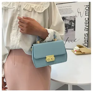 Detailed view of glacier blue small square bag with woven handle and gold metal clasp