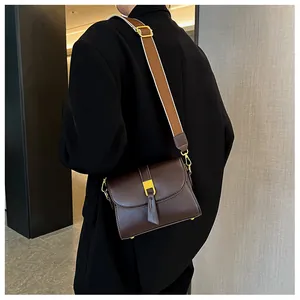 Detail of dark brown matte leather crossbody bag with adjustable bicolor fabric strap