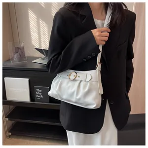 Dettaglio della borsa a spalla arricciata bianca con fibbia dorata su blazer nero