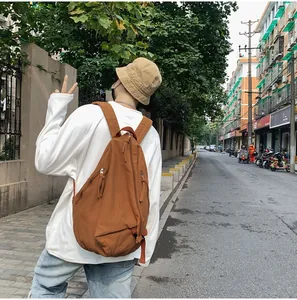 Mochila de lona marrón caramelo usada por un modelo masculino en un entorno urbano