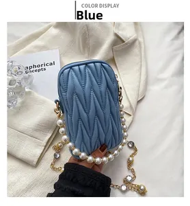 Detail view of blue quilted phone bag with pearl handle and gemstone chain strap