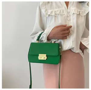 Detail of green crossbody bag featuring a braided handle and gold metal clasp closure