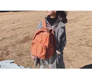 Dettaglio di uno zaino vintage in tela arancione indossato da una modella all'aperto
