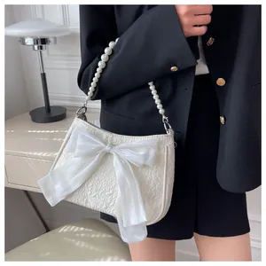 Dettaglio borsa a tracolla jacquard bianca con fiocco di seta e tracolla di perle