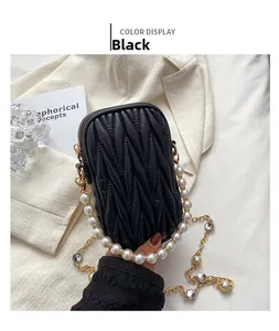 Detail of black matelassé mini bag with pearl handle and golden chain strap