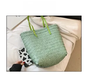 Size comparison of a mint green woven beach tote with a smartphone and a magazine