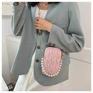 Detailed texture of pink quilted mini phone bag with faux pearl and metal chain straps