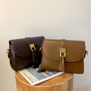 Vintage style brown leather crossbody bag with golden metal buckle and retro aesthetic