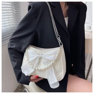 Dettaglio della borsa jacquard bianca con fiocco in chiffon e catena di perle elegante