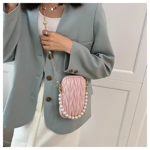 Detail of pink pleated mini crossbody bag with pearl handle and gold chain strap