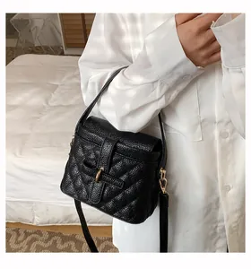 Dettaglio della borsa in pelle nera trapuntata con chiusura dorata su una modella