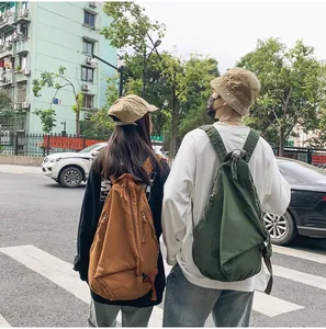 Modelos en la calle usando mochilas de lona vintage en color marrón y verde
