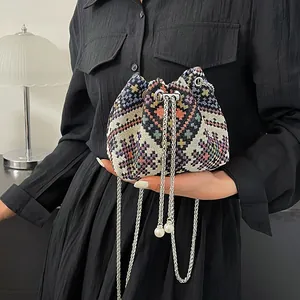 Dettaglio del motivo etnico intrecciato colorato su borsa a secchiello con catena e perle