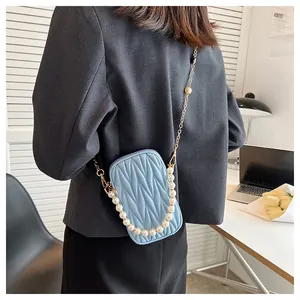 Detail of light blue quilted mini crossbody phone bag with gold chain and pearl handle