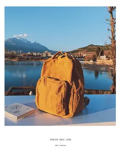 Dettaglio di uno zaino in tela giallo senape dal design vintage chic in riva al lago