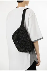 Close-up of black denim chest bag featuring distressed frayed edges and street style texture