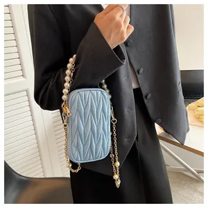 Detail of light blue quilted mini crossbody bag with pearl and gold chain strap