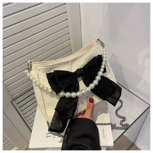 Dettaglio borsa plissettata panna con grande fiocco nero e manico di perle decorativo