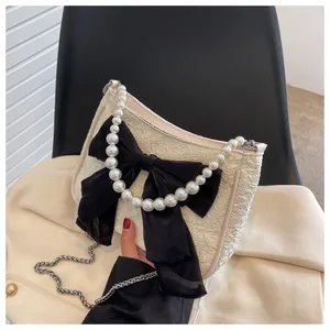 Dettaglio del tessuto jacquard crema con fiocco in raso nero e manico di perle eleganti
