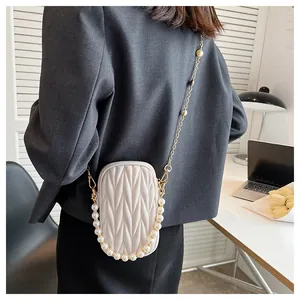 Quilted crossbody phone bag with pearl handle and gold chain strap on model