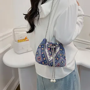 Dettaglio di motivi etnici geometrici su borsa a secchiello in lino blu con perle
