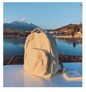 Dettaglio del tessuto dello zaino in tela beige con sfondo lago e montagne al tramonto