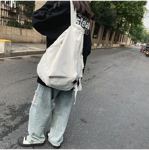 Vista exterior de un bolso bandolera de lona blanca grande llevado por una modelo