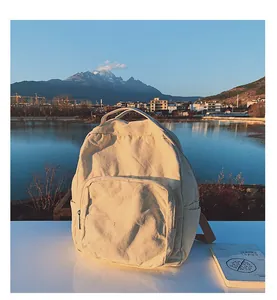 Dettaglio dello zaino in tela bianco panna con tasche laterali e trama lavata vintage
