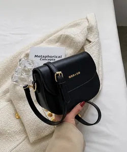 Κοντινή λήψη μαύρης τσάντας σέλας με χρυσό λογότυπο και υφή συνθετικού δέρματος