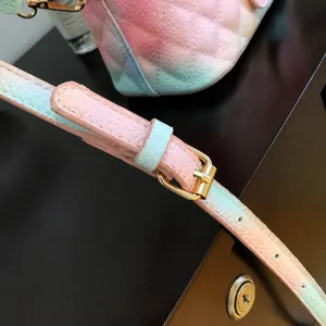 Dettaglio tracolla regolabile su borsa in pelle sfumata rosa e verde con fibbia dorata