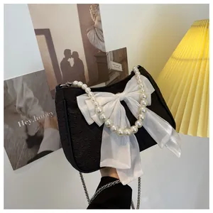 Dettaglio borsa in tessuto nero con grande fiocco bianco e manico di perle chic