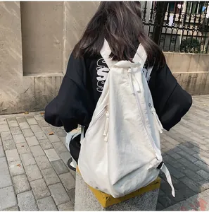 Vista trasera de modelo con mochila de lona blanca y detalle de cremallera diagonal