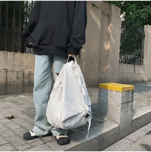 Detalle de la cremallera lateral en la mochila de lona blanca con un diseño asimétrico