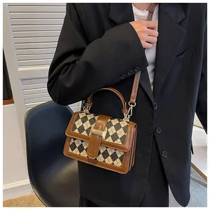 Dettaglio borsa a tracolla vintage a rombi con fibbia dorata e bordo in pelle marrone