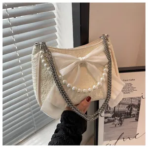 Dettaglio della borsa a tracolla bianco crema con fiocco e catena di perle decorativa