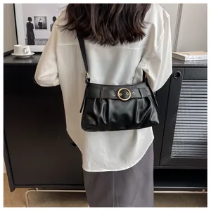 Dettaglio di una borsa a spalla nera arricciata con fibbia dorata e cintura ad occhielli