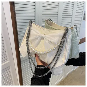 Dettaglio di borsa a mano bianca a pieghe con grande fiocco in organza e manico di perle