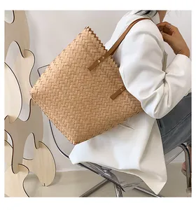 Detailed side view of a large woven straw tote bag with brown leather straps on a model
