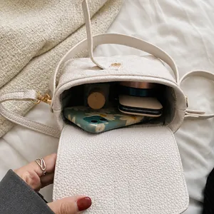 Vista interna della borsa a tracolla crema con smartphone e accessori per il trucco