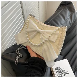 Dettaglio della borsa bianco crema con fiocco morbido ed elegante manico di perle