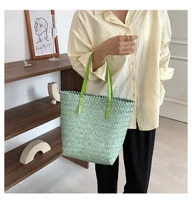 Detail of mint green woven tote bag featuring emerald straps and gold rivet accents