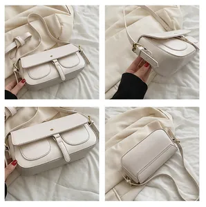 Dettaglio borsa a tracolla in pelle crema con due tasche frontali e finiture dorate