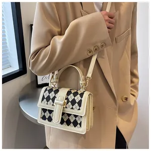 Dettaglio della piccola borsa a tracolla quadrata con motivo trapuntato beige e fibbia oro