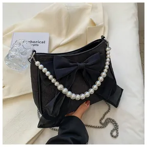 Dettaglio della borsa in jacquard nero con grande fiocco e manico in perle bianche