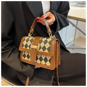 Dettaglio della piccola borsa quadrata vintage in tela a quadri con finiture in pelle marrone