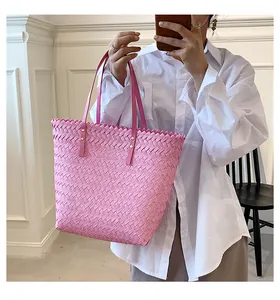 Detail of pink woven tote bag with jagged edges and leather handles with gold rivets